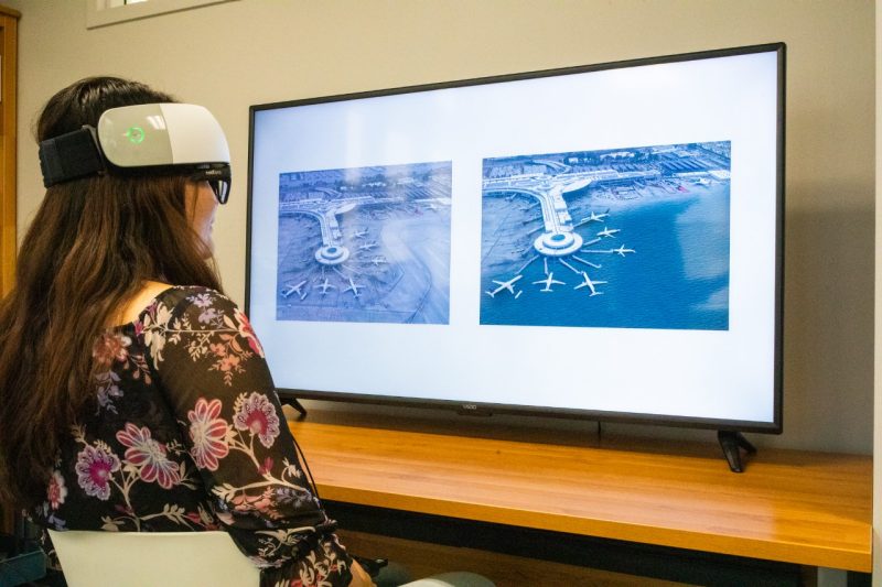 A student undergoing a brain activity study in front of a monitor with two similar airport images but one is under water.