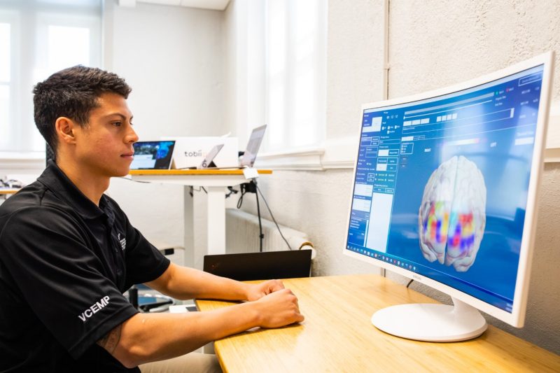 A student looking at a monitor showing brain activity.
