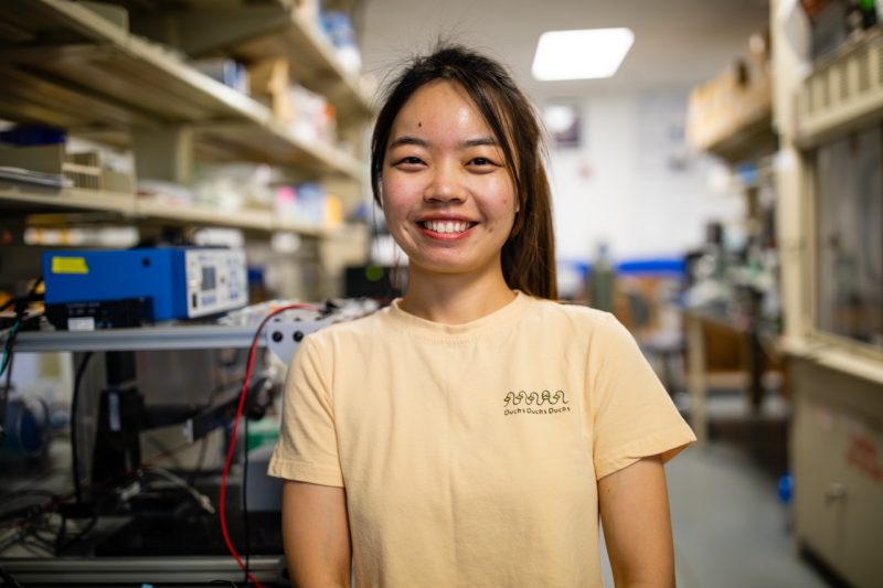 A grad student poses for a photo after working in a lab.