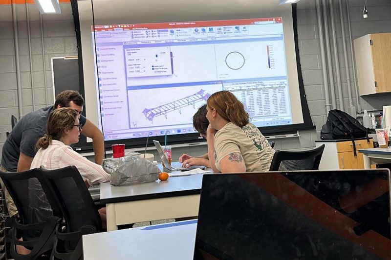 Team members review CAD drawings of the design on a screen.