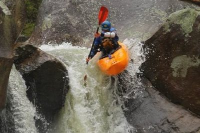 Tripp Shealy going over a medium-sized waterfall in a kayak.