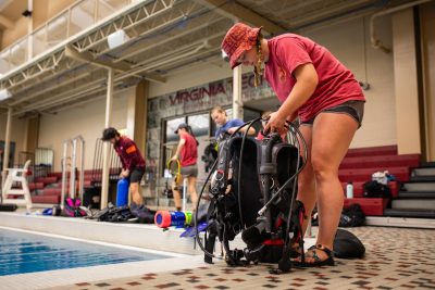Cara Johnston prepares her scuba her gear by the indoor pool.
