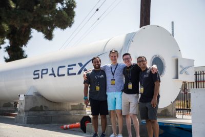 Proud Virginia Tech Hyperloop team members pose arm in arm in front of the Hyperloop track at SpaceX.