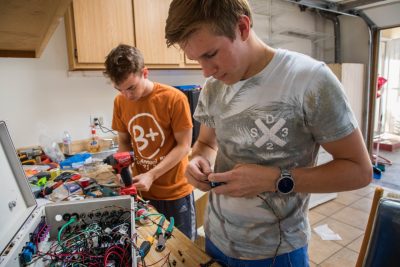 Two Virginia Tech work on electrical components at a workbench.