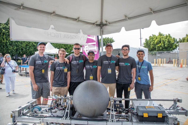 Seven Hyperloop team members pose for a group shot in front of their Hyperloop pod.
