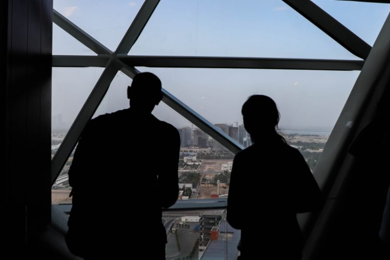 Two students looking out the window of a tall building overlooking the city