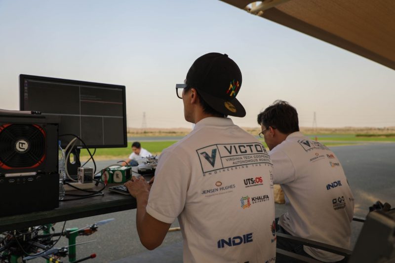 Two students working at a computer to fly a drone